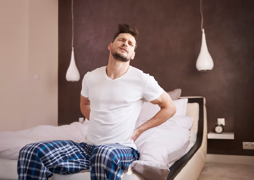 Изображение мужчины на кровати с болью в спине